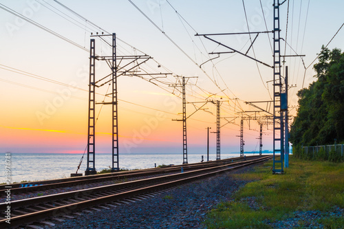 Beautiful landscape of a railroad and towers of traction line on the background of the sea at twilight, Sochi, Russia 