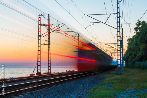 Beautiful landscape of a railroad with motion blurred train on the background of the sea at twilight, Sochi, Russia 