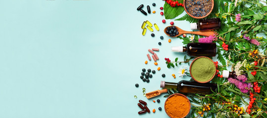 Holistic medicine approach. Healthy food eating, dietary supplements, healing herbs and flowers. Turmeric, dried lavender, spirulina powder in wooden bowls, fresh berries, omega acid capsules