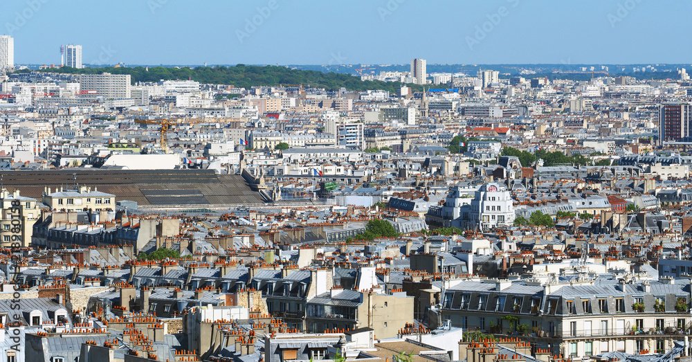 Aerial cityscape of Paris in France, Montmartre, panoramic view. View of Paris from Sacre Coeur Basilica in France in summer day. Roofs in residential quarters. Gare du Nord, railway station
