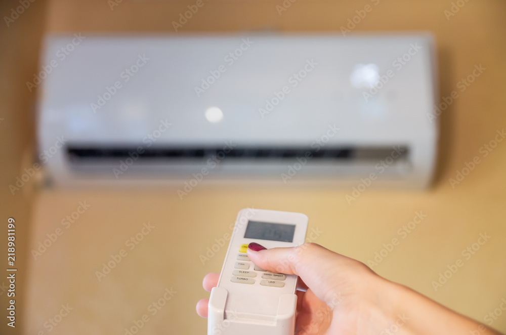 Air conditioner inside the room with woman operating remote controller. / Air conditioner with remote controller Air conditioner inside the room with woman operating remote controller. / Air conditioner with remote controller