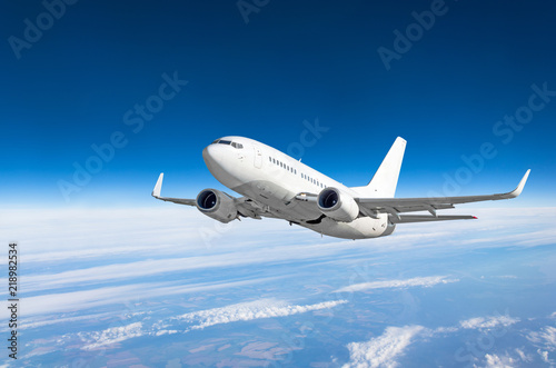 Passenger airplane fly on a hight above clouds and blue sky.