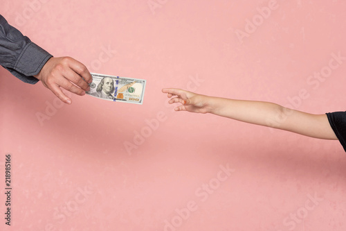 The child's hand stretches for money. Father gives his daughter pocket money.