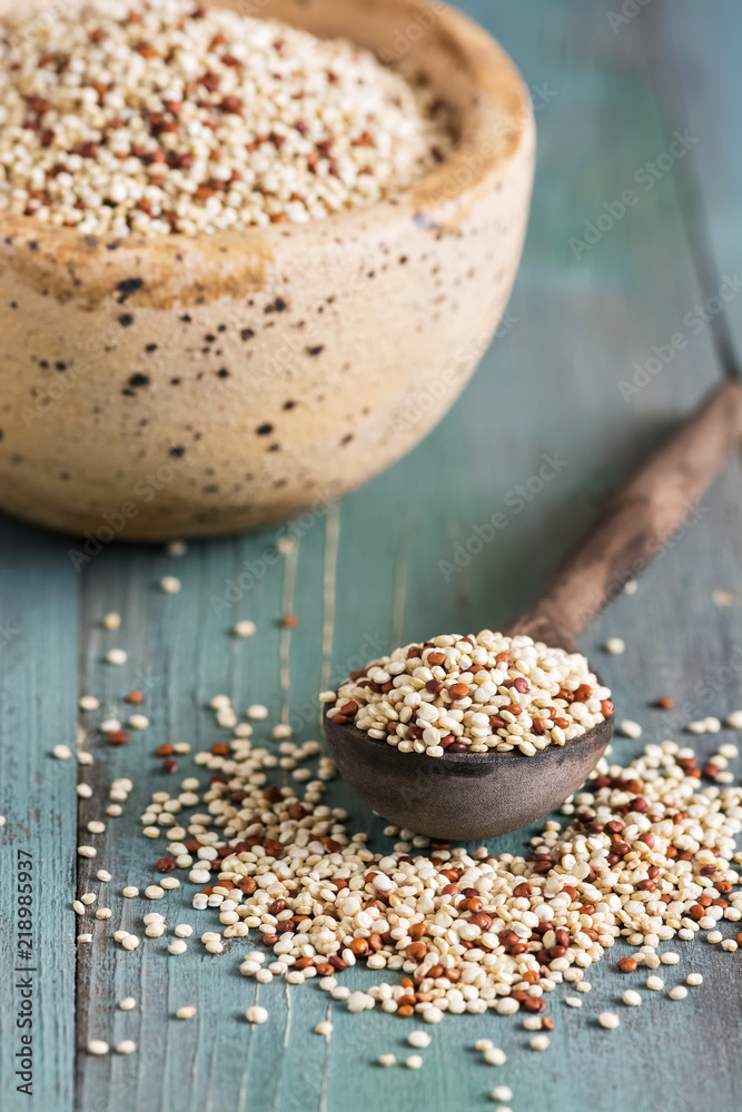 Raw mixed quinoa in wooden spoon closeup on rustic background. Selective focus. Raw mixed quinoa in wooden spoon closeup on rustic background. Selective focus.