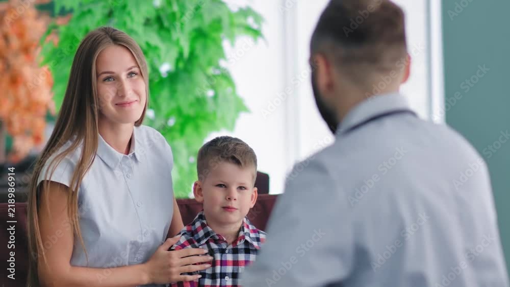 Portrait of handsome young European mother and little son at reception of male doctor Portrait of handsome young European mother and little son at reception of male doctor