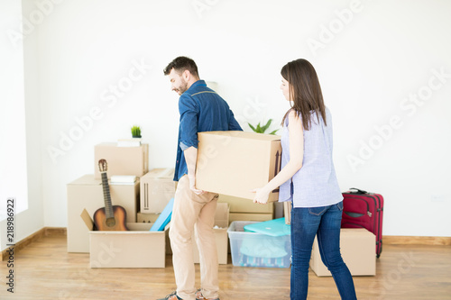 Woman Assisting Man Carrying Heavy Box While Moving House © AntonioDiaz