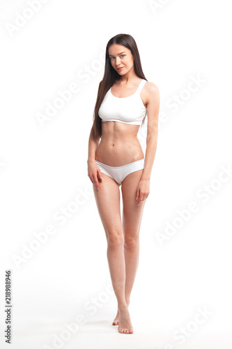 Slim young woman in underwear on white background