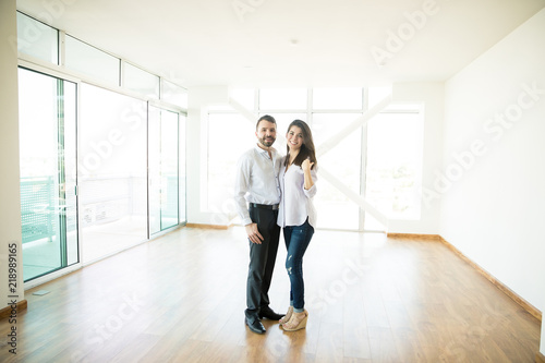 Smiling Mid Adult Owners Standing In New House
