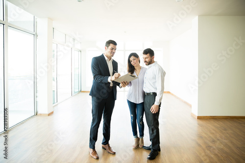 Realtor Explaining Agreement To Couple In New Apartment photo