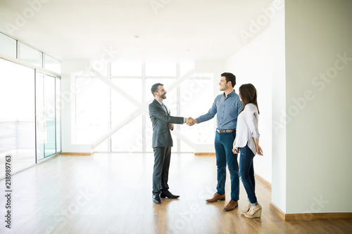 Estate Agent Greeting Couple During Visit To New Home