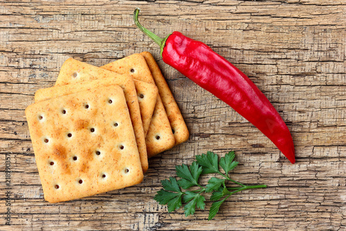 Foto Crackers, hot pepper and parsley on a wooden background.