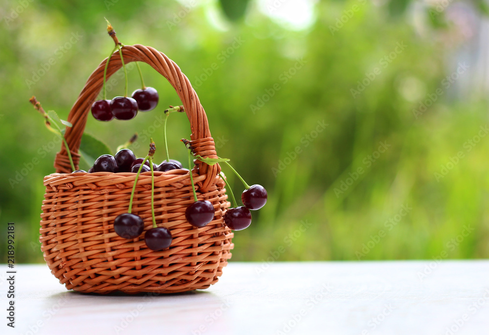 Cherry in a wooden basket with leaves and copy space.