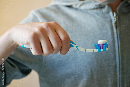 Hand holding tooth brush. Close-up of young man's hands is holding a toothbrush and placing toothpaste on it.