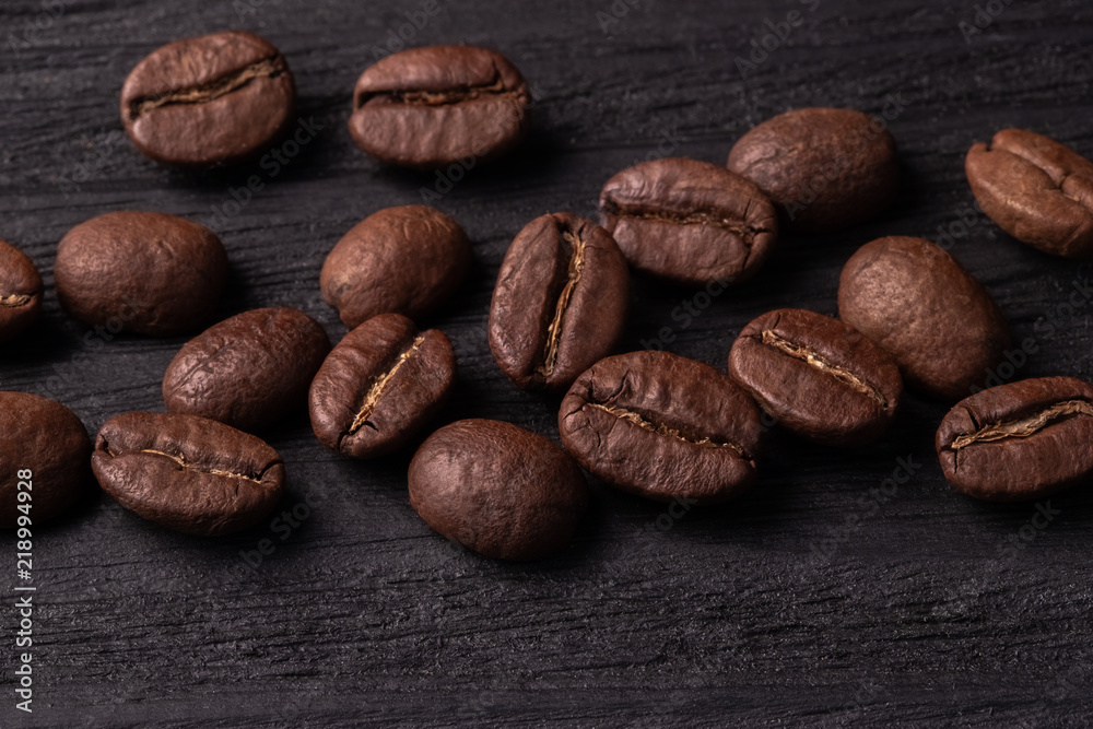 Naklejka premium coffee arabica grains scattered on a wooden table