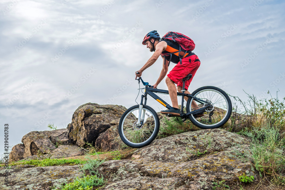 Cyclist descending down the rock on a mountain bike, an active lifestyle.