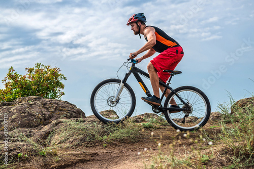 Cyclist in a helmet and with a backpack riding down the rock on a mountain bike, an active lifestyle.