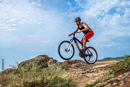 Concept of extreme cycling, a biker on a mountain bike on the blue sky background, free space.