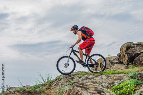 Concept of extreme cycling, a biker on a mountain bike on the blue sky background, free space. © mihakonceptcorn