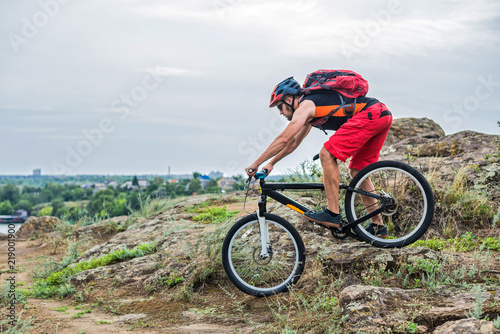 Cyclist riding down the rock on a mountain bike, extreme enduro cycling.