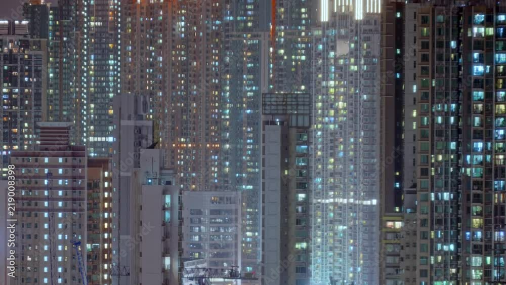 Day to night transition timelapse of Hong Kong apartment buildings. Chinese crowded city with lights turning on and off at midnight. Fast paced modern Asian night-scape time lapse in urban metropolis. Day to night transition timelapse of Hong Kong apartment buildings. Chinese crowded city with lights turning on and off at midnight. Fast paced modern Asian night-scape time lapse in urban metropolis.