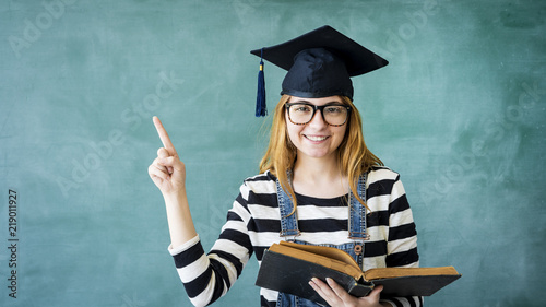 Young student girl pointing up on green chalkboard photo