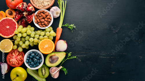 Healthy food clean eating selection: Vegetables, fruits, nuts, berries and mushrooms, parsley, spices. On a black background. Free space for text.
