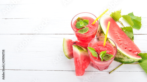 Watermelon juice with mint and ice in a glass. Melon. On a white wooden background. Free space for text. Top view.