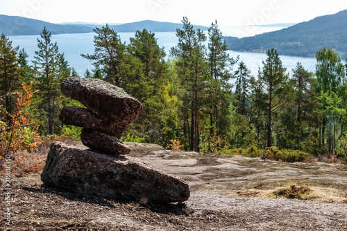 Stack of stones marking hiking trail. Beautiful views of mountains, forest and lake in the background. Skule mountain, high coast in northern Sweden.