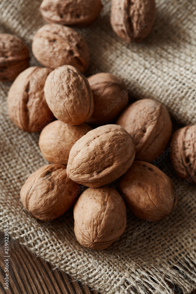 Walnuts and kernels with burlap fabric on a dark rusty wood backdrop Walnuts and kernels with burlap fabric on a dark rusty wood backdrop