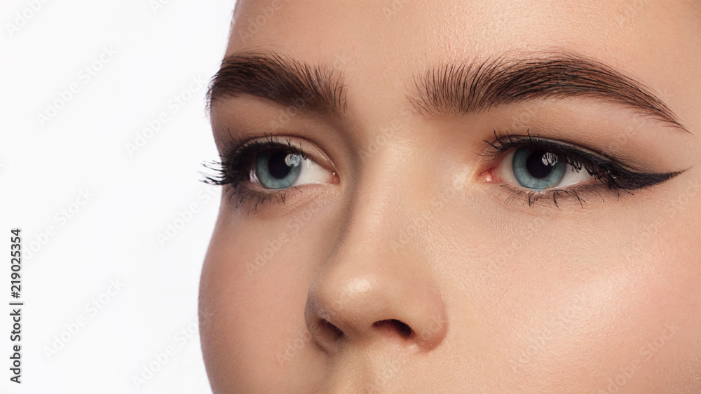 Close up view of blue woman eye with beautiful golden shades and black eyeliner makeup. Classic make up. Perfect brows. Studio shot Close up view of blue woman eye with beautiful golden shades and black eyeliner makeup. Classic make up. Perfect brows. Studio shot