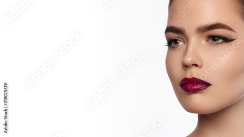 Close-up portrait of a beautiful young woman with full claret lips, eyeliner and contact lenses on a white background. Cosmetology, Cosmetics, Medicine, Eye Correction, Halloween