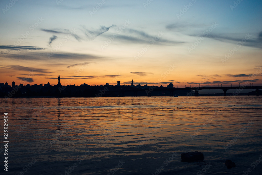 Skyline, Kiev city in the evening. The right bank at sunset across the Dnieper River. Silhouette of a city on a sunset background.