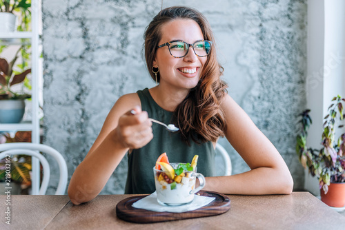 Foto Young cheerful woman eating fruit salad.