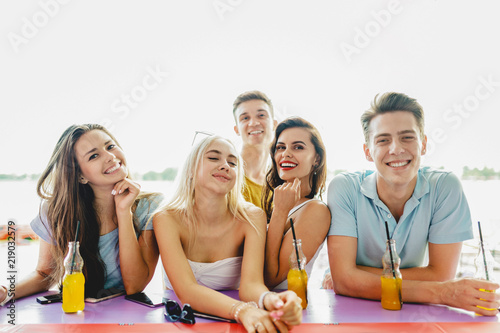 A company of good-looking friends laughing, drinking yellow cock