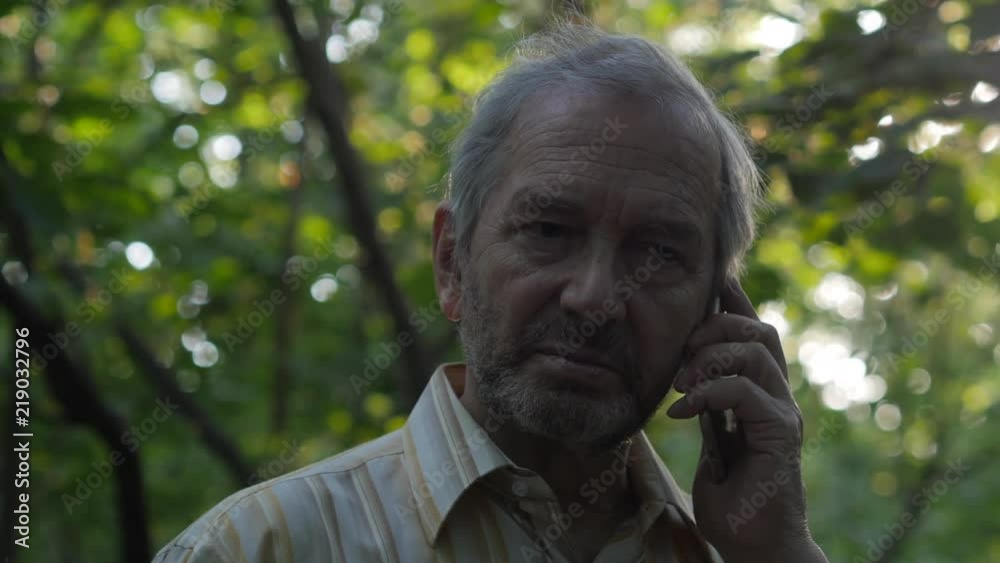 Elderly Bearded Man Talking On The Smartphone In The Forest Elderly Bearded Man Talking On The Smartphone In The Forest