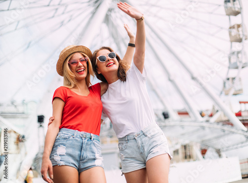 Happy brightful positive moments of two stylish girls hugging on street in city. Closeup portrait funny joyful attarctive young women having fun, smiling, lovely moments, best friends photo