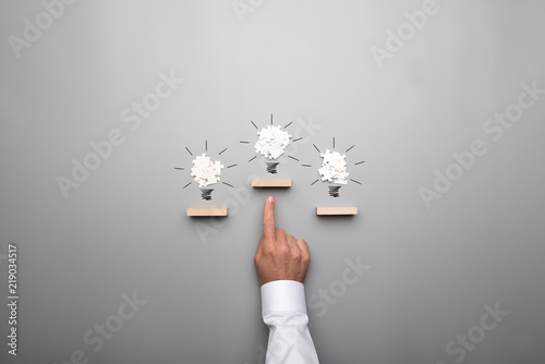 Three light bulb formed by white puzzle pieces placed on wooden pegs photo