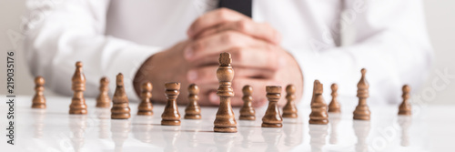 Businessman planning strategy with chess figures on white table photo