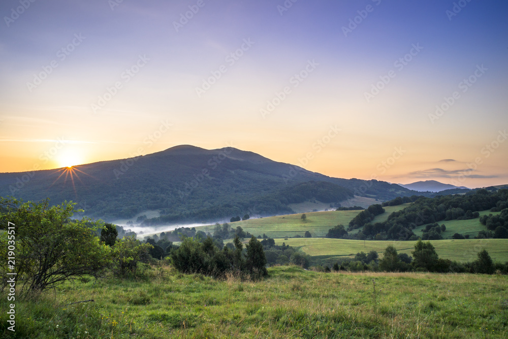 Obraz premium Połonina Caryńska w Bieszczadach o wschodzie słońca. Widok z przełęczy Wyżnej. W oddali Tarnica