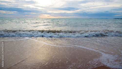 Sand beach with sea waves in the sunset.