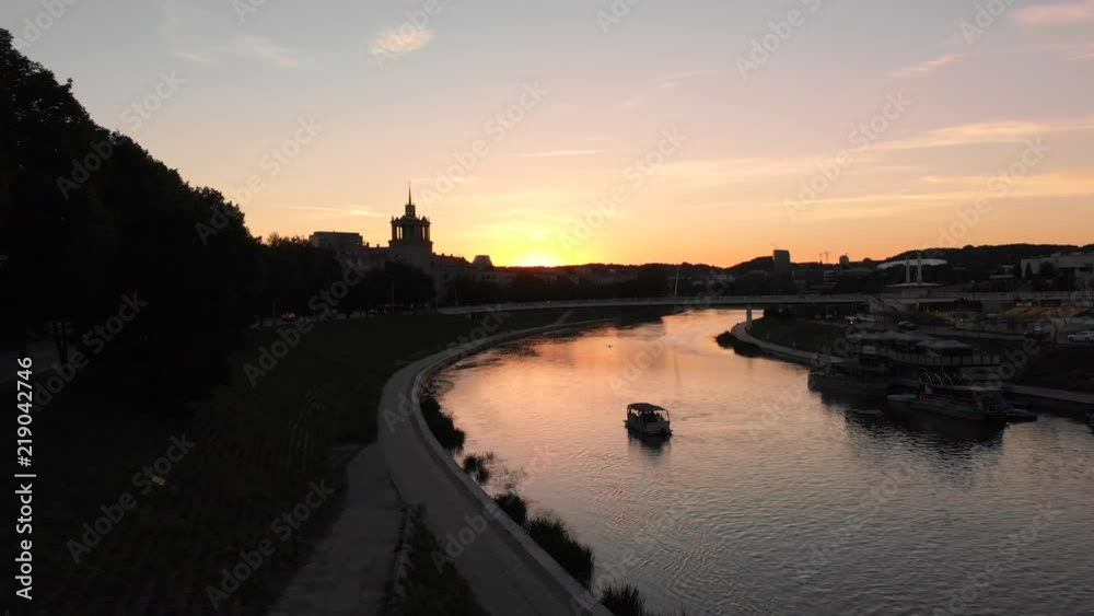 4k aerial evening flight over the curve of the river, during sunset, small boat is sailing further, sky is orange blue. 4k aerial evening flight over the curve of the river, during sunset, small boat is sailing further, sky is orange blue.
