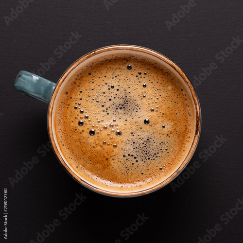 Cup of coffee on black background. Copy space. Square. Top view. Flat lay.