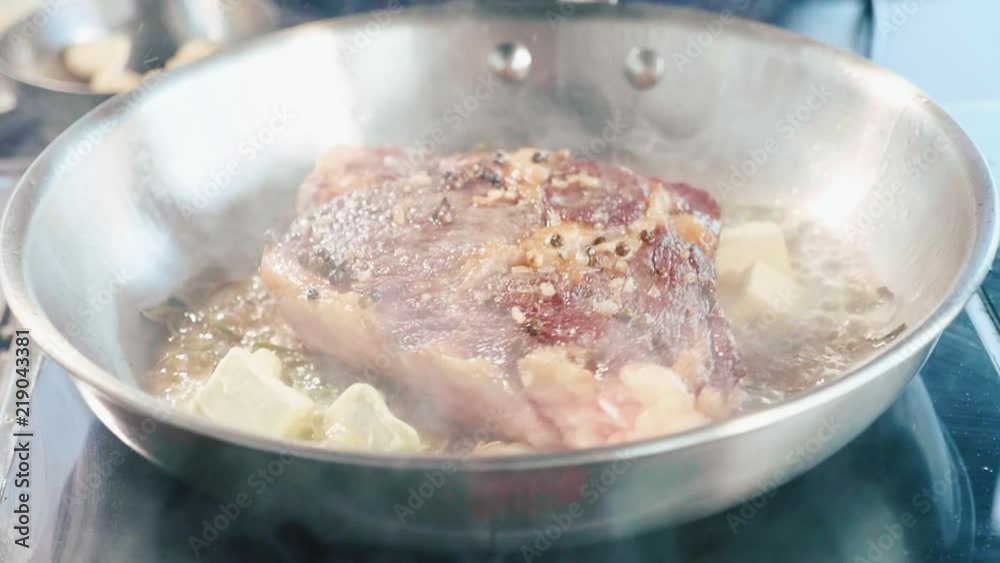 Meat steak with seasonings and herbs hissing on frying pan, close-up Meat steak with seasonings and herbs hissing on frying pan, close-up