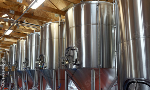 Row of shiny metal micro brewery tanks.