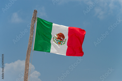 Mexican flag over blue sky in Tulum, Mexico.
