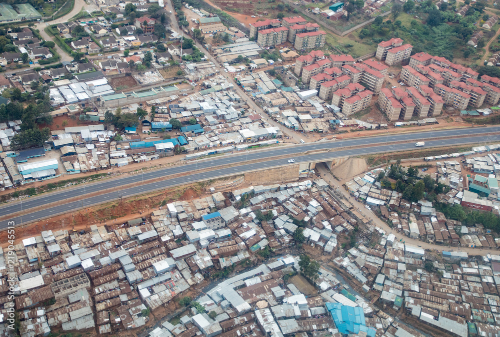 Aerial view of Nairobi, Kenya, showing modern apartment blocks alongside a sprawling township of tin roofs and squalor
