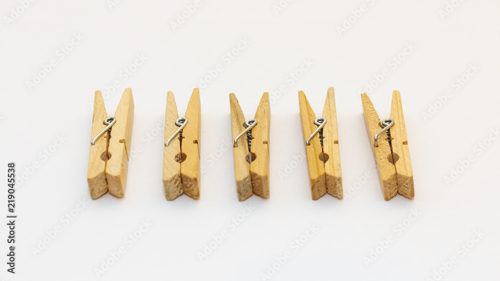 Isolated wooden clothes pegs lying side by side on a white background Isolated wooden clothes pegs lying side by side on a white background
