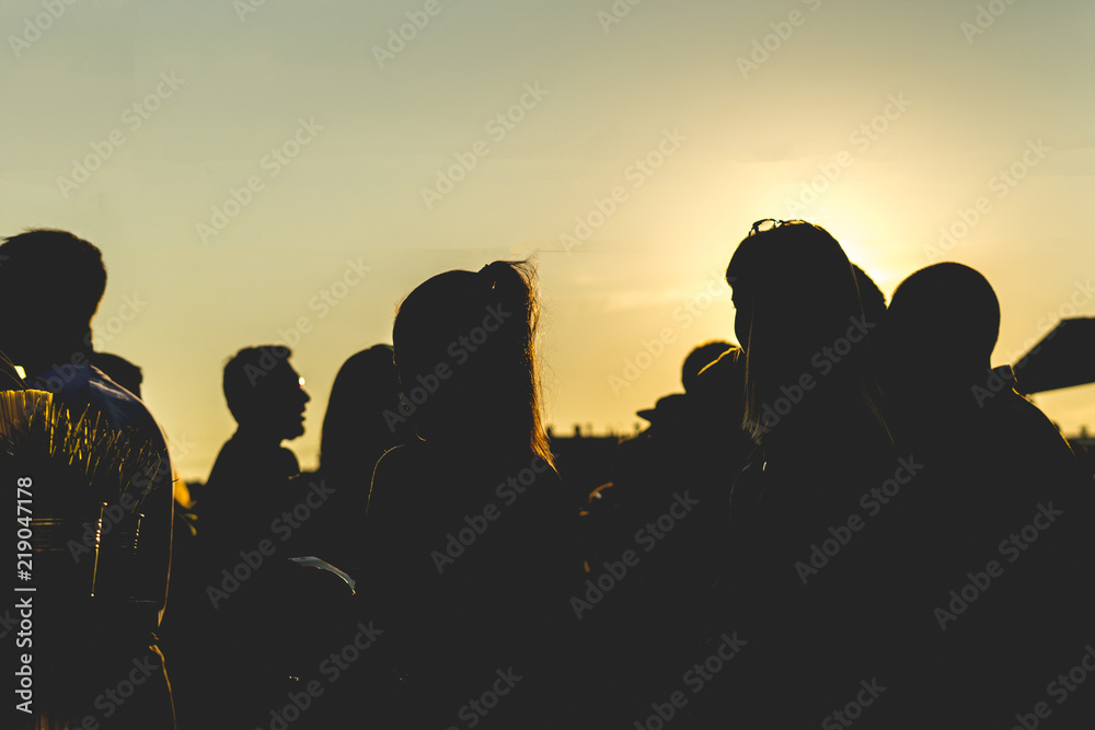 silhouette of group of friends walking in the city during sunset against sky