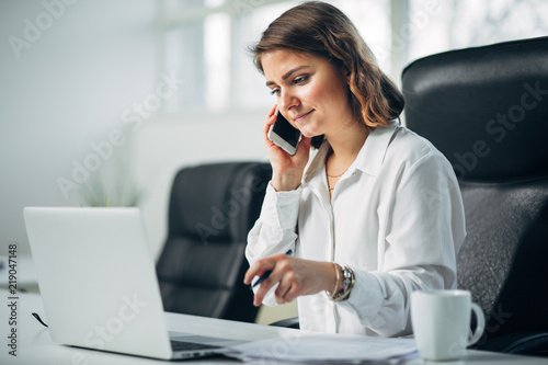 Young woman in office talking on a cell phone photo