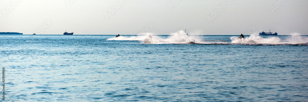 Obraz premium people ride a water motorcycle in the sea, panorama